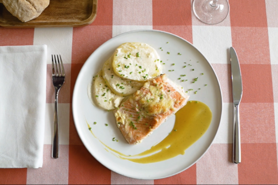 Mantel a cuadros rojos en el que se puede ver un plato de salmón con patatas y salsa de miel.
